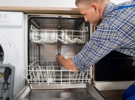 Young Man In Overall With Toolbox Repairing Dishwasher